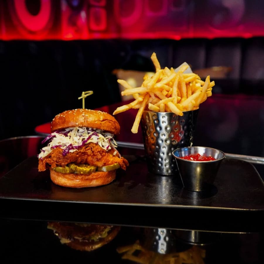 Spicy fried chicken sandwich with coleslaw, pickles, and fries served on a tray