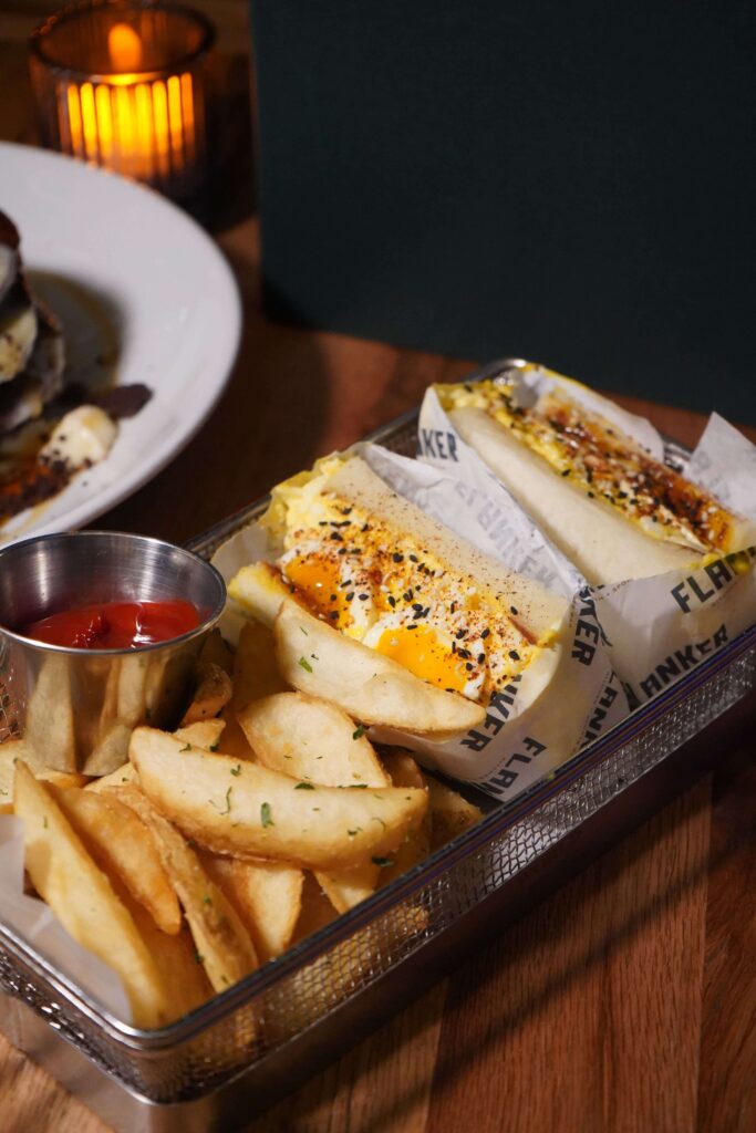 Image pop-up Breakfast sandwiches topped with eggs and seasoning, served with French fries and ketchup at Flanker.