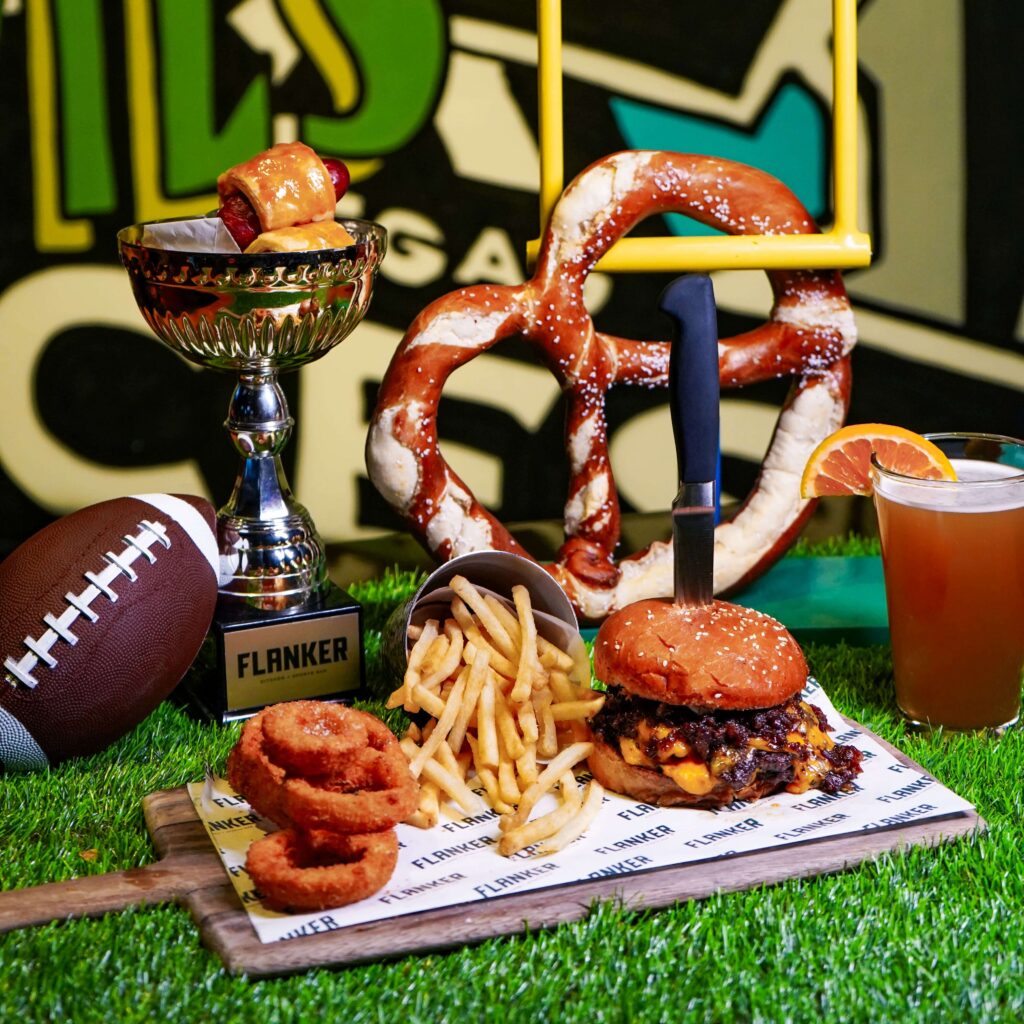 Image pop-up Cheeseburger with fries and onion rings displayed with a large pretzel, football, drink, and Flanker trophy.