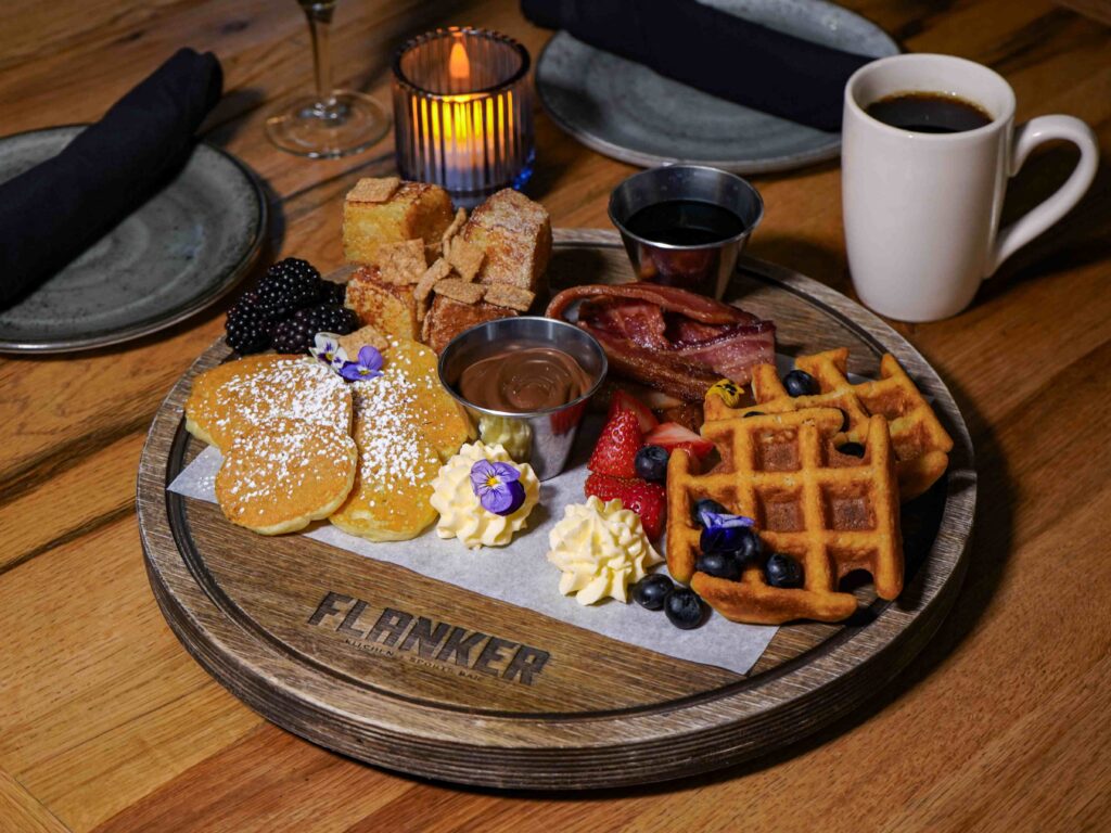 Image pop-up Breakfast board with pancakes, waffles, French toast bites, bacon, berries, whipped cream, and dipping sauces.