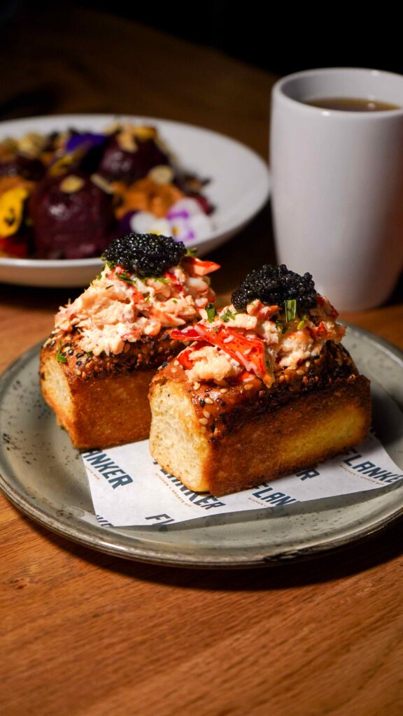 Image pop-up Two toasted rolls filled with lobster and herbs, each topped with black caviar.